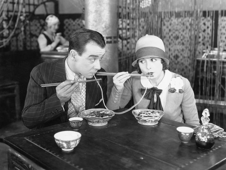 Vintage couple at a restaurant sharing a spaghetti string