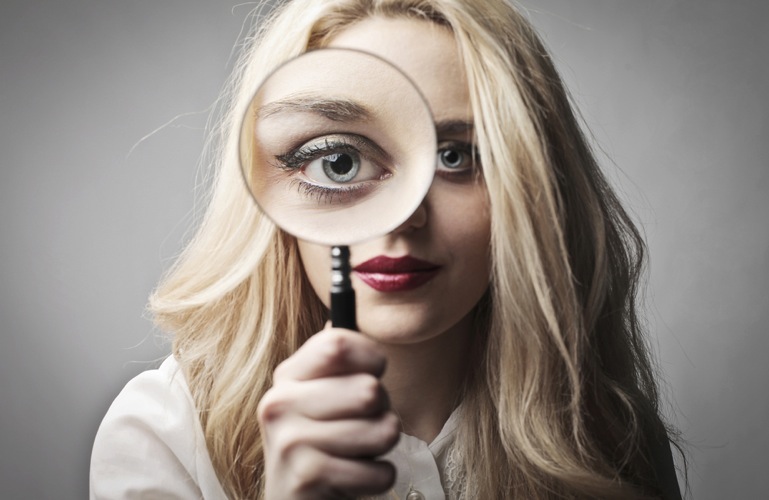 A woman looks through a magnifying glass
