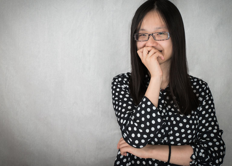 Nervous young woman holding her hand to her mouth