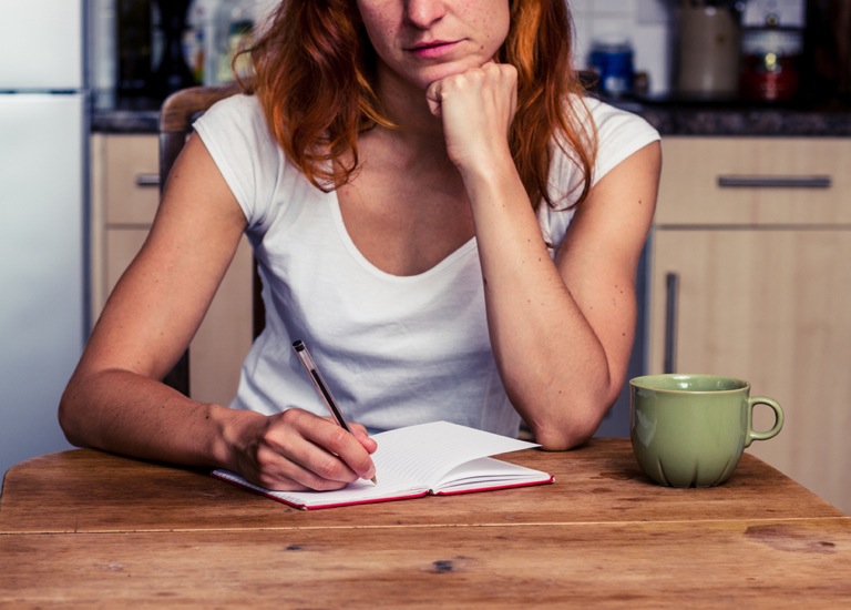 Woman sitting in her kitchen writing