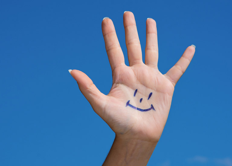 Hand showing a smiley face and five fingers