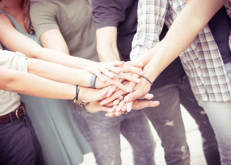 group of friends piling up hands in unity