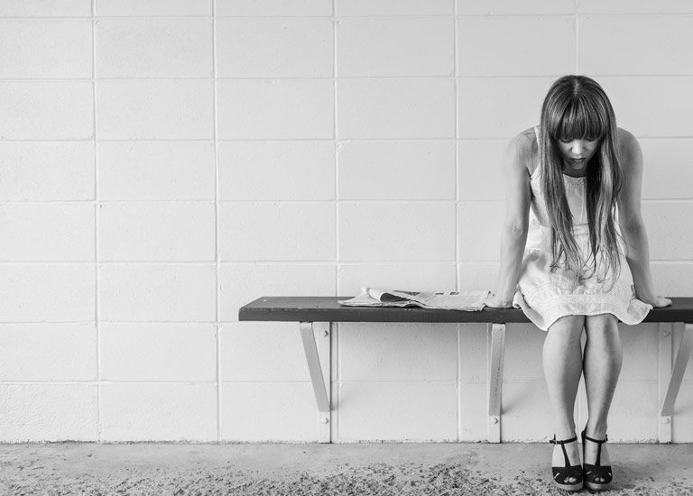 Girl sitting, waiting on a bench