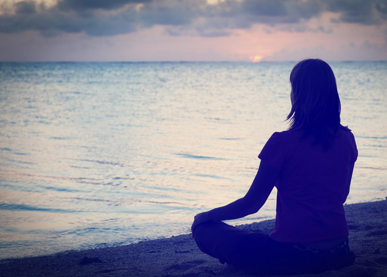 Woman meditating on a beach