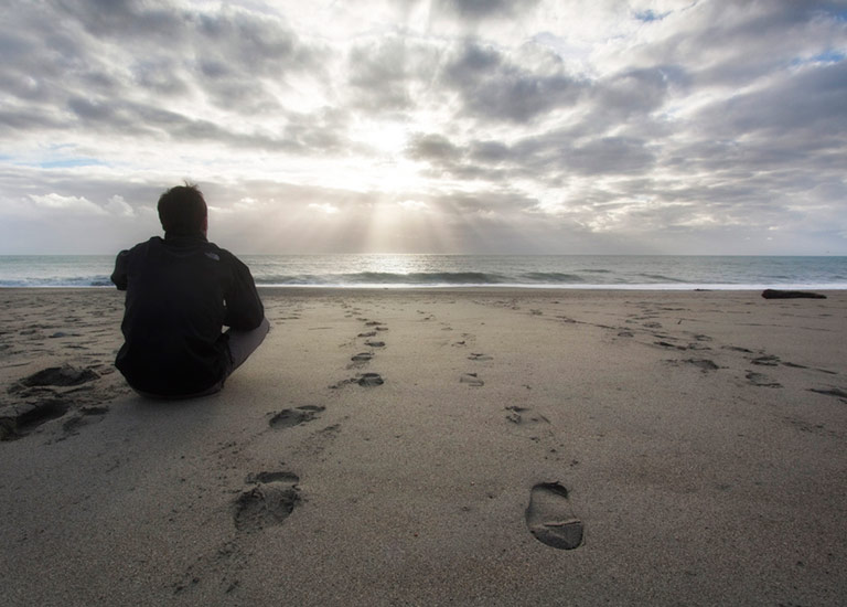 Man sitting reflectively on the beach