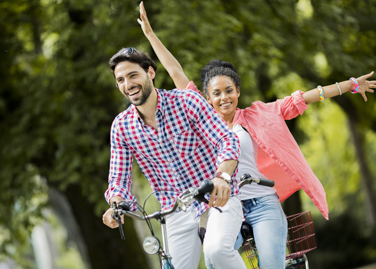 A young couple riding a tandem bicycle