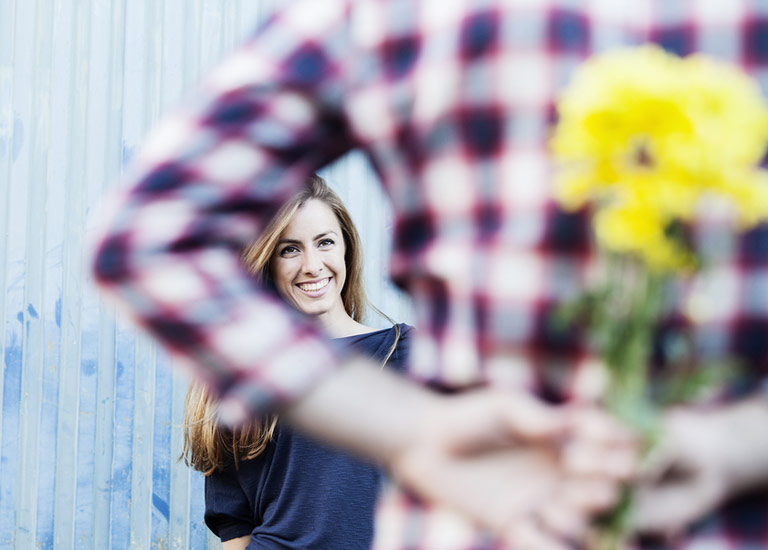 Man hiding a bunch of flowers behind his back