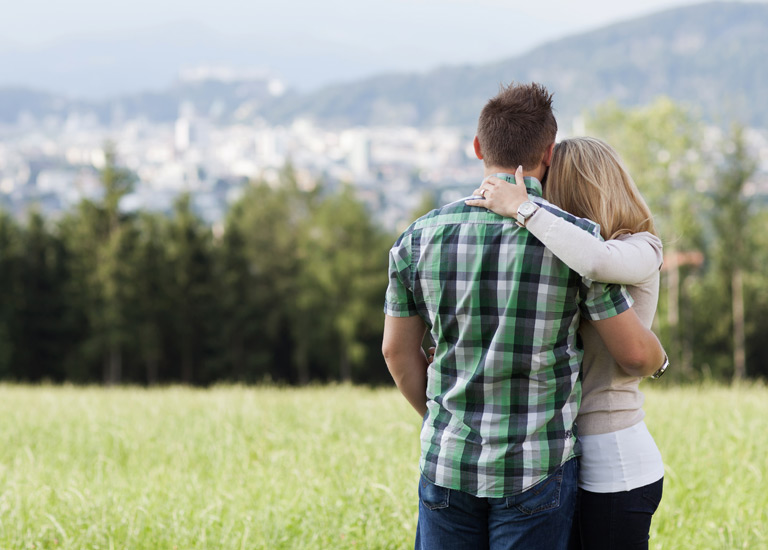 A couple embracing, looking out at a viewpoint