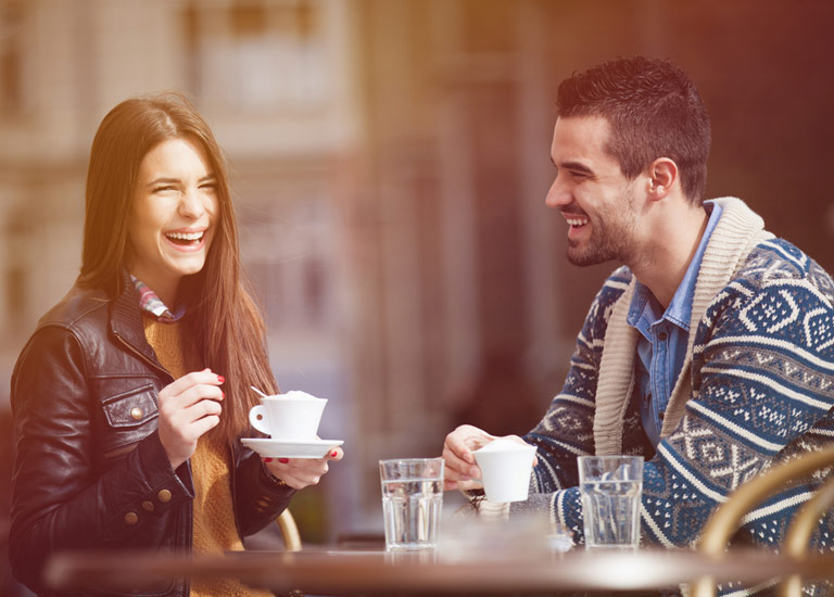 A man and woman laughing whilst at a cafe