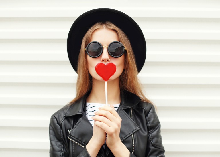 Woman holding heart-shaped lollipop