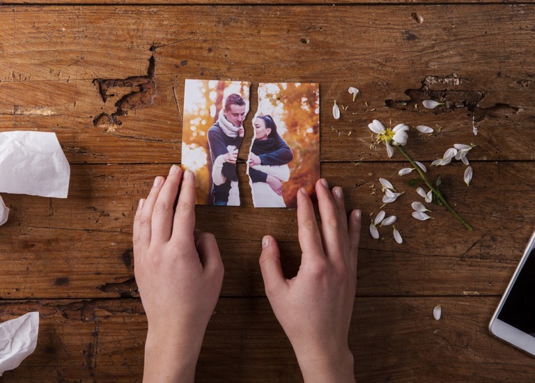 Woman looking at a photograph, torn in two