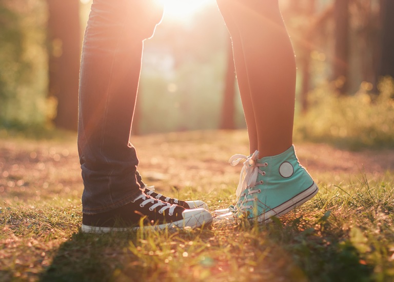 Young couple kissing whilst standing in sunlight