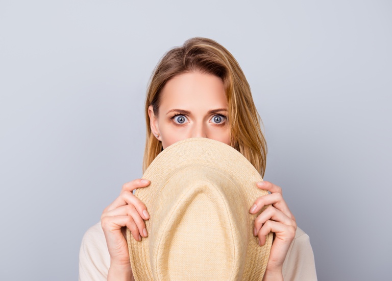 Woman hiding behind a hat