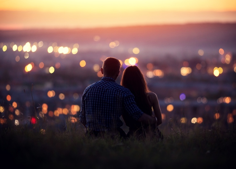 A couple overlooking a city at sunset