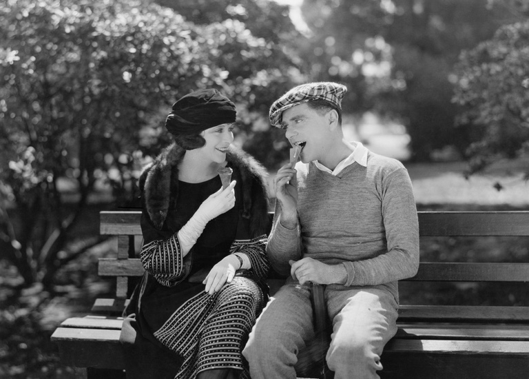 Black and white photo of a vintage couple sitting on bench