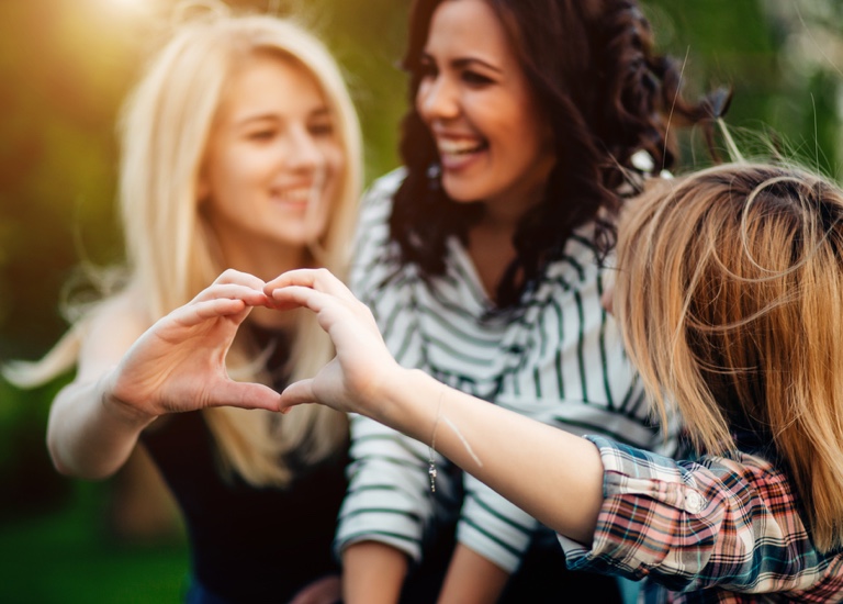 Friends laughing and making heart gesture