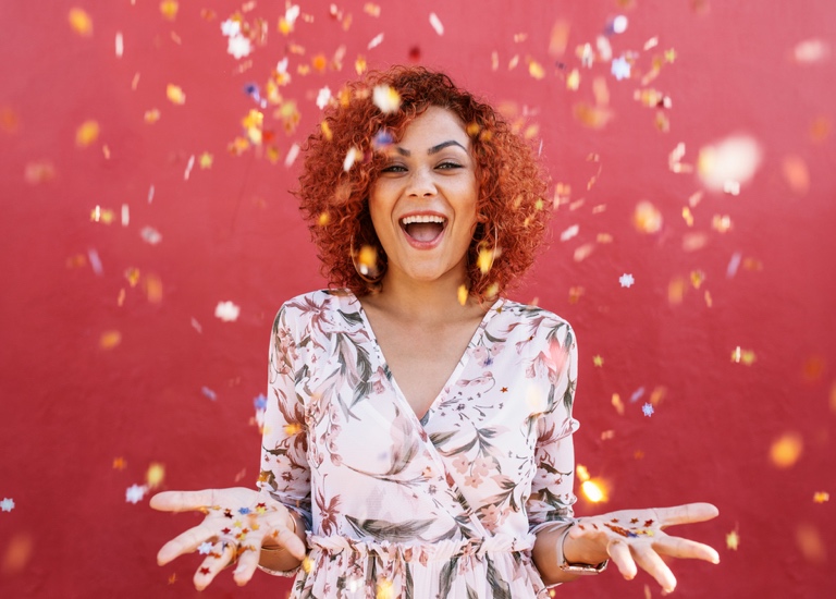 A happy woman with hands open, raining confetti