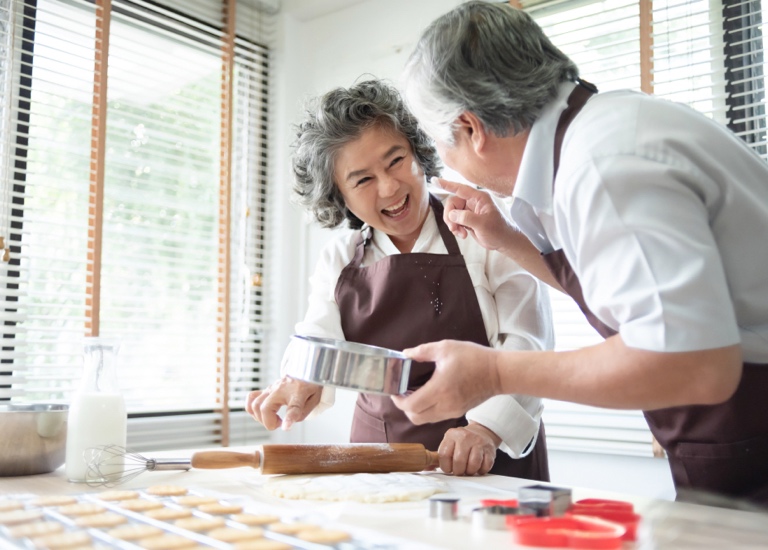 A couple baking cookies together and laughing