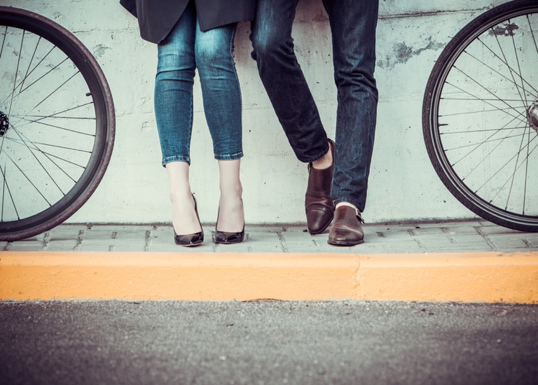 A young couple standing by a wall next to bicycles