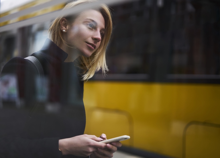 A young women checks her phone whilst walking down the street