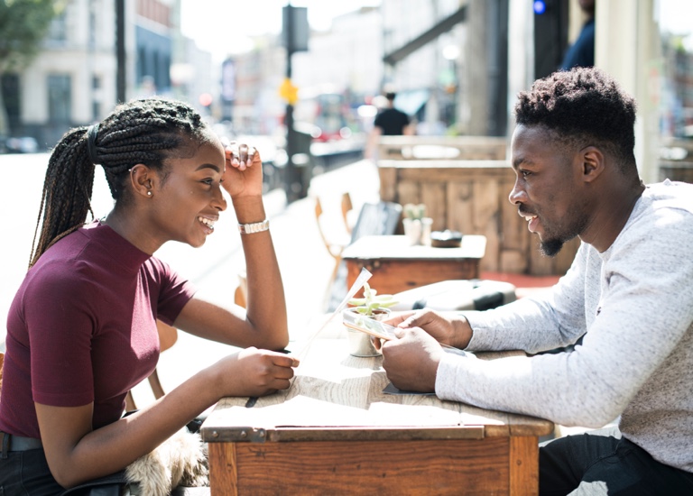 A couple sat opposite at a table reading a menu together