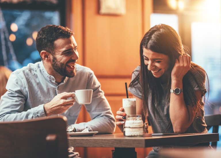 A man and a woman drinking coffee and laughing together