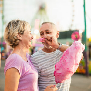 Couple eating candyfloss at fairground - 8 fun extrovert date ideas - Christian Connection blog