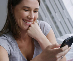 Woman smiling using dating app - How to use the 'Discover' filters on Christian Connection for effective searching - Christian Connection blog