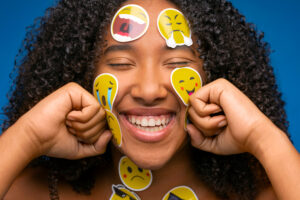 Laughing woman with emoji stickers - 3 important ways to manage your emotions while dating - Christian Connection blog